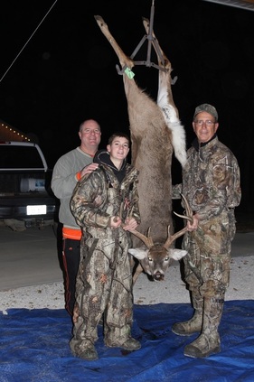 Deer hanging upside down after a recent kill. Dale Sader and family members surround
